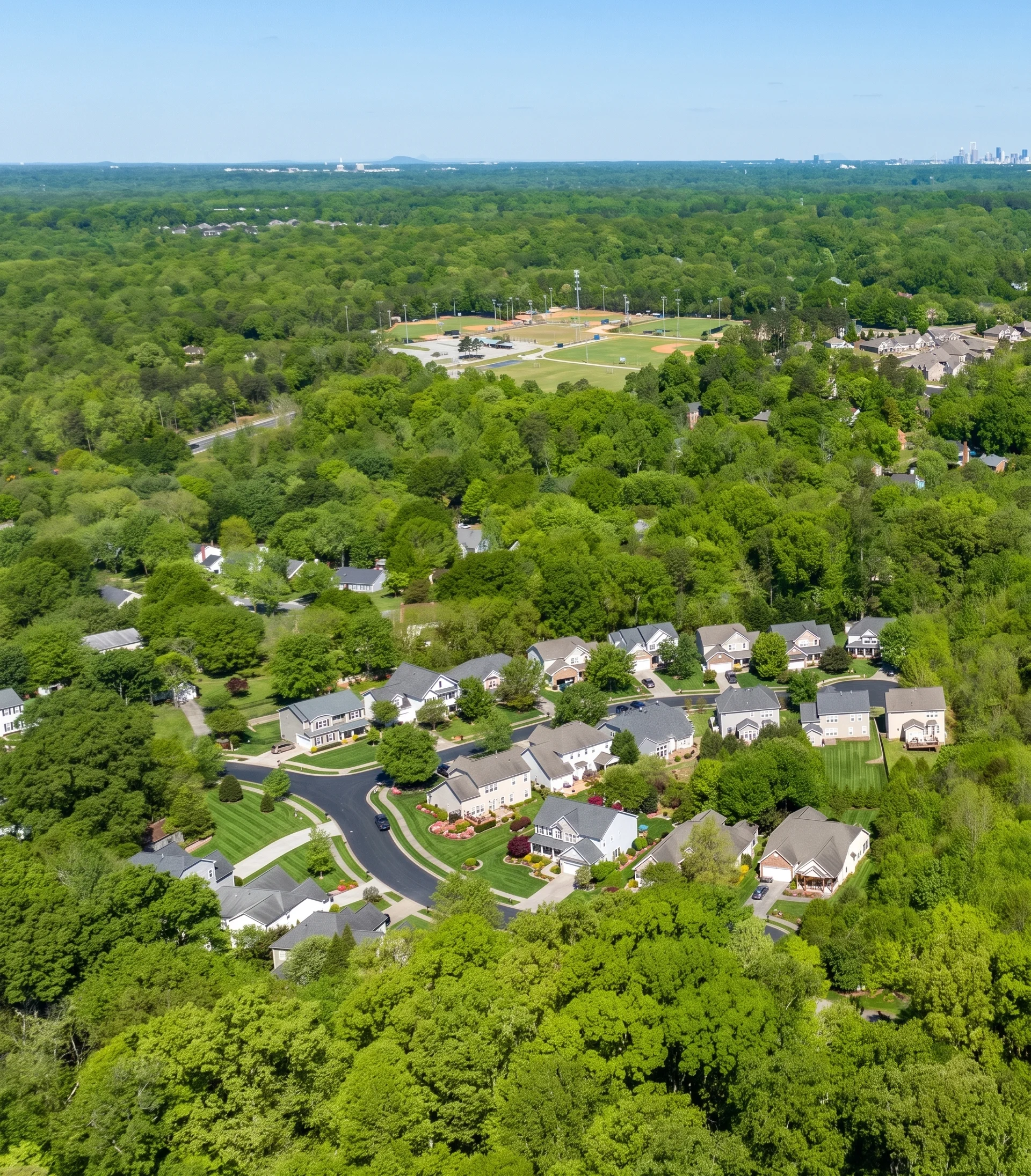 An aerial view of homes, ball fields, and tree canopy in Matthews